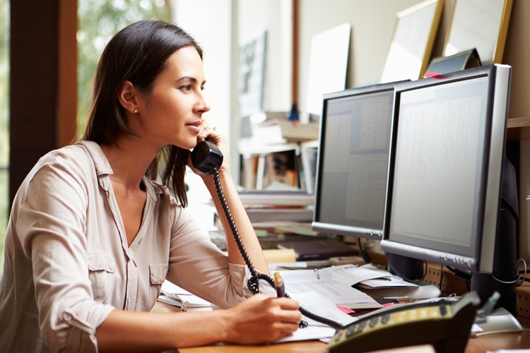 Woman on the phone looking at computer Woman on the phone looking at computer