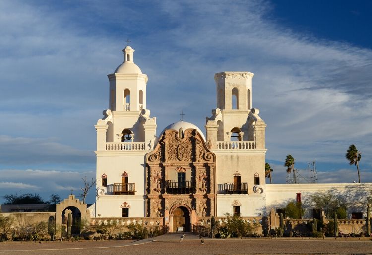 San Xavier Mission at sunrise with dogs playing outside, Tucson, Arizona